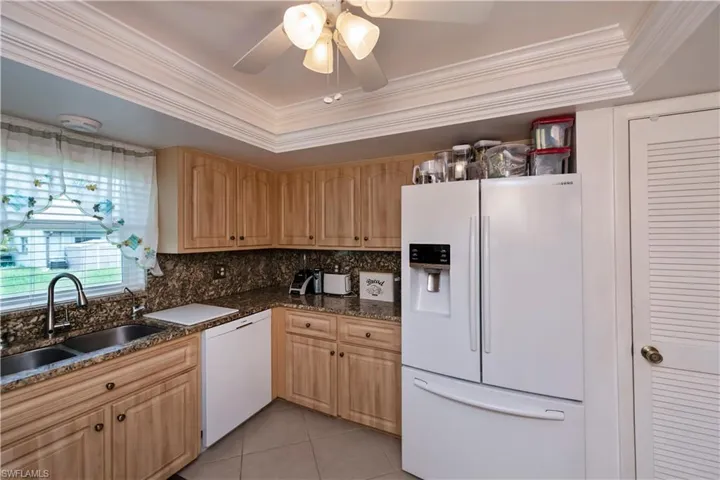 Kitchen with ceiling fan, granite countertops and backsplash, white appliances, a raised ceiling, pantry and sink