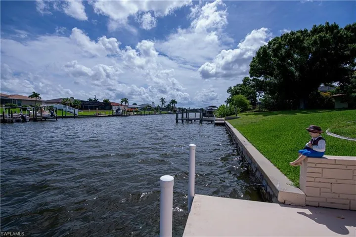 View of dock with a water view and a lawn
