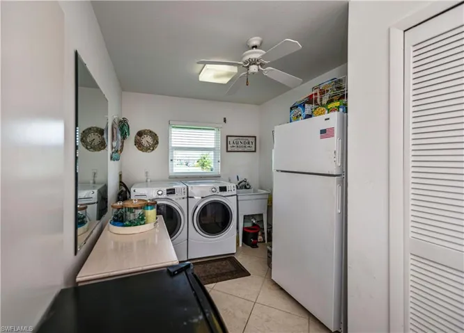 Washroom featuring ceiling fan, hookup for a washing machine, light tile flooring, sink, and washer and clothes dryer, large closet