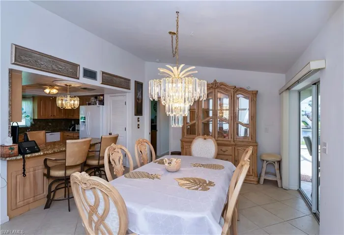 Tiled dining space featuring an inviting chandelier with access to screened pool area