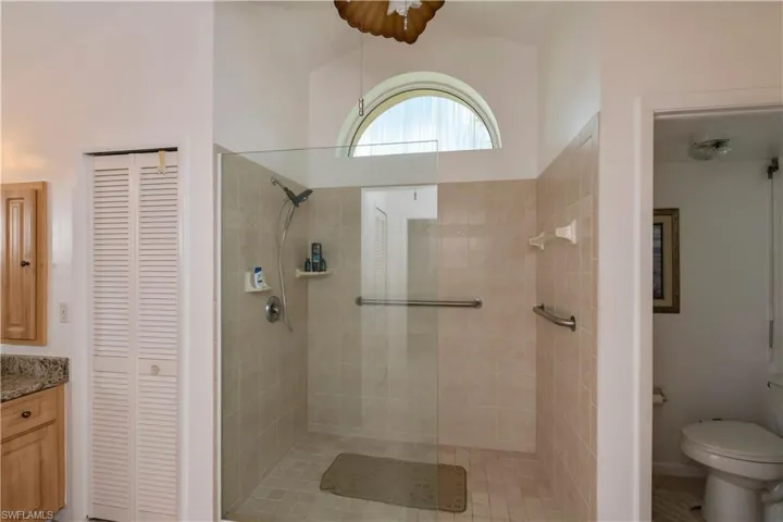 Bathroom featuring vaulted ceiling, tiled shower, seperate vanities, linen closet with attached large safe