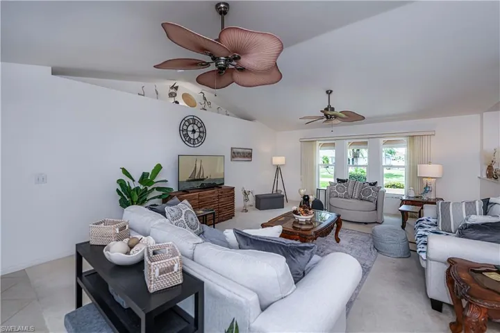 Large living room with lofted ceiling, tile flooring, and ceiling fan