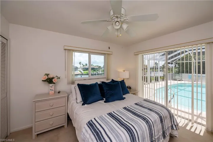 Guest bedroom with a walk-in closet, ceiling fan, and access to outside screened pool area