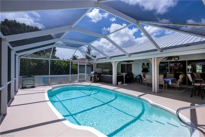 View of swimming pool with a patio area, screen enclosure, and grilling area