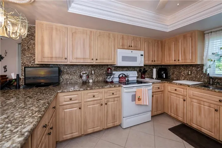 Kitchen with granite countertops and backsplash, and white appliances