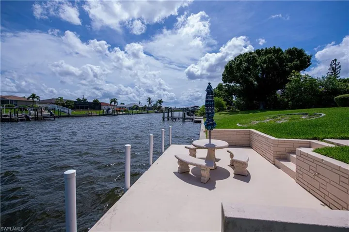 View of dock with a lawn and a water view
