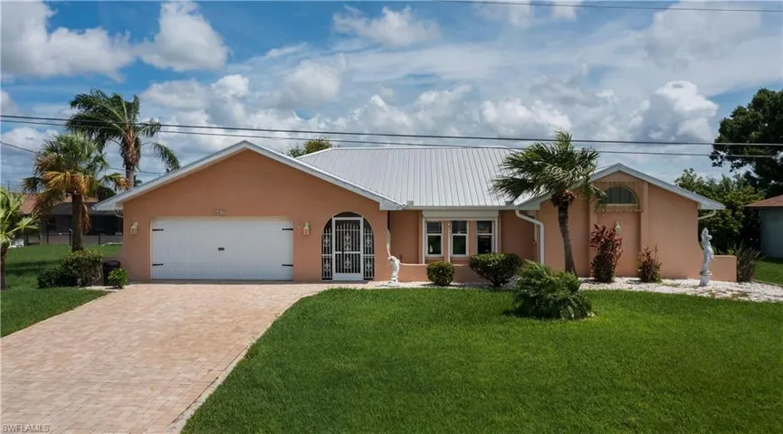 Single story waterfront, gulf access, pool home featuring a garage and a front yard
