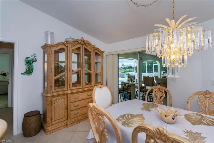 Tiled dining area featuring an inviting chandelier and vaulted ceiling