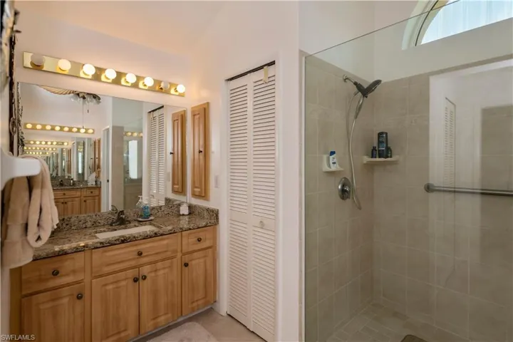 Bathroom with tile flooring, tiled shower, and seperate vanities with large linnen closet