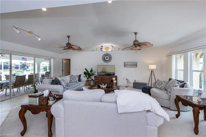 View of living room area from dining room, featuring ceiling fan, vaulted ceiling, a wealth of natural light, and rail lighting