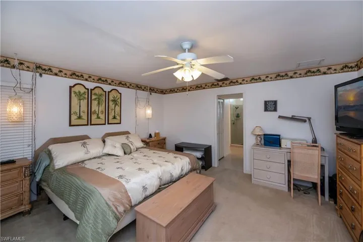 Bedroom with connected bathroom, ceiling fan, and carpet floors, walk-in closets, with access to screened pool lanai