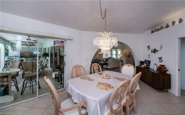 Tiled dining room featuring vaulted ceiling and ceiling fan with access to screened lanai