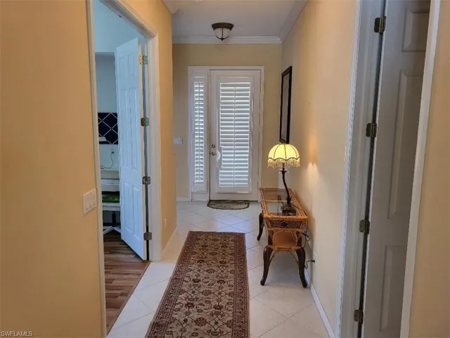 Hallway with light tile patterned floors and ornamental molding