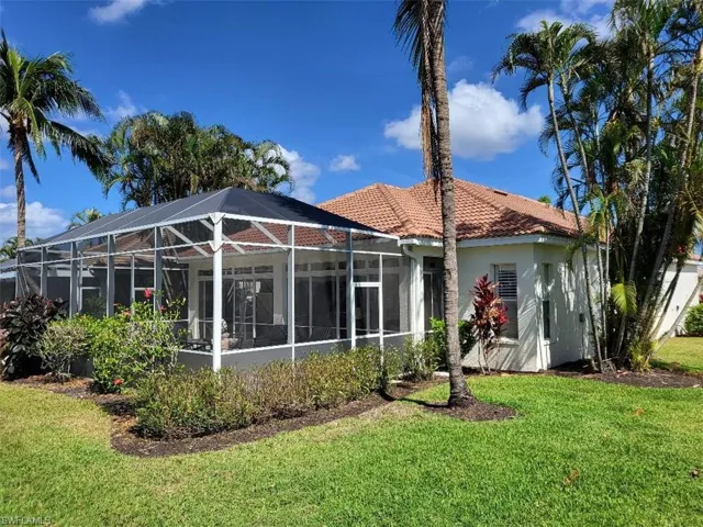 Back of house with glass enclosure, a lawn, a sunroom, and stucco siding