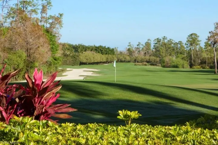 View of property's community with view of golf course, view of wooded area, and a putting green