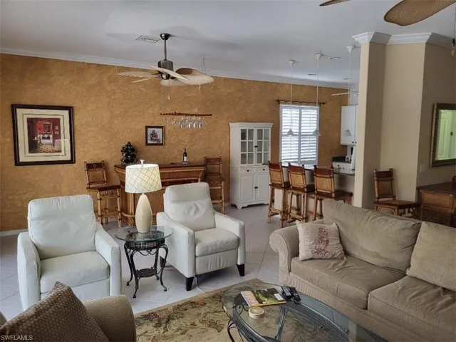 Tiled living area with a ceiling fan and ornamental molding