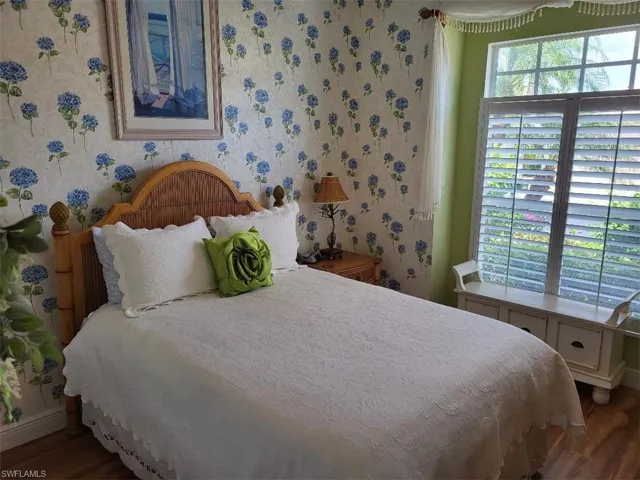 Bedroom with wood finished floors and wallpapered walls