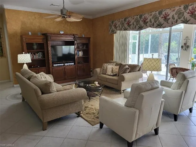 Living area featuring light tile patterned floors, ornamental molding, and ceiling fan