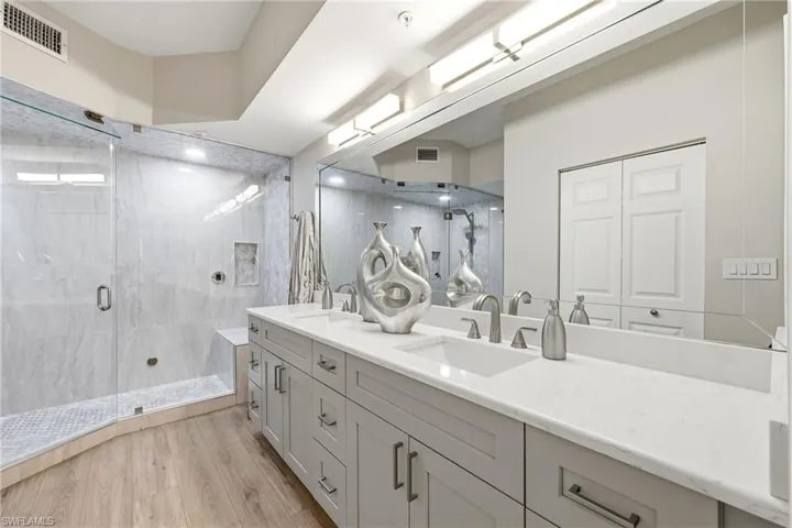 Full bath featuring a stall shower, double vanity, light wood-type flooring, and a closet