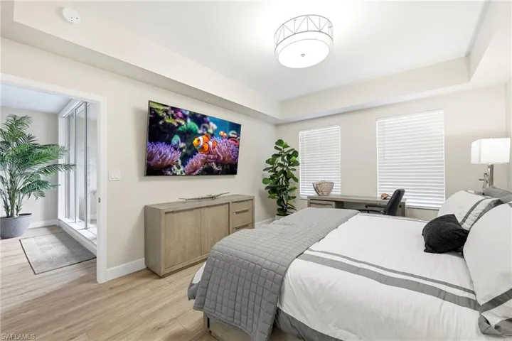 Bedroom with wood finished floors and a tray ceiling