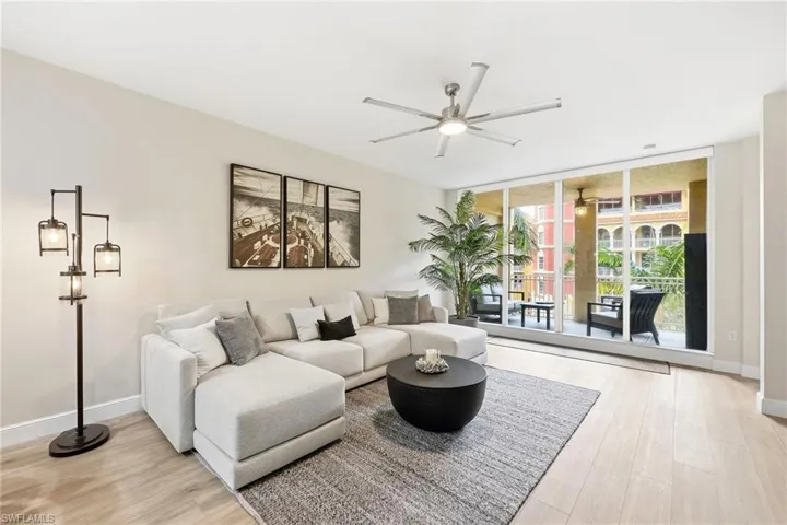 Living area with expansive windows, light wood-style floors, and a ceiling fan