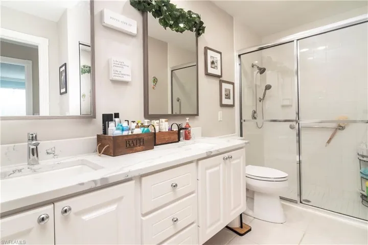 Full bath featuring a stall shower, tile patterned flooring, double vanity, and toilet