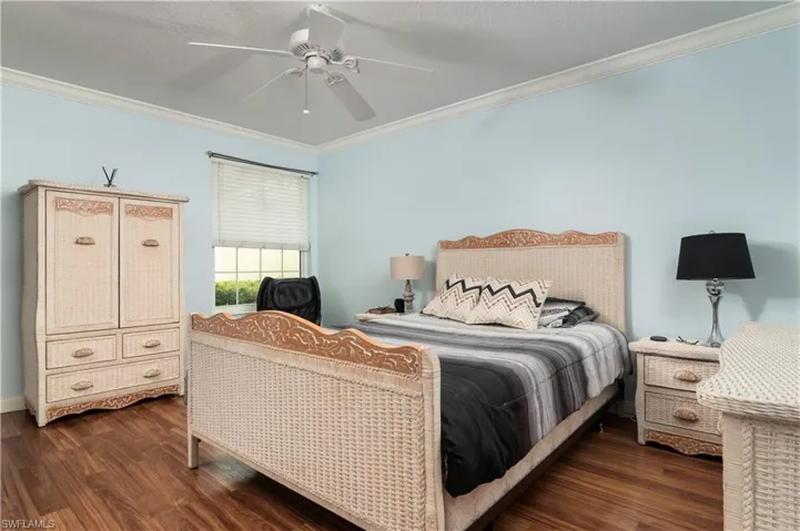 Bedroom featuring ornamental molding, dark wood finished floors, and ceiling fan