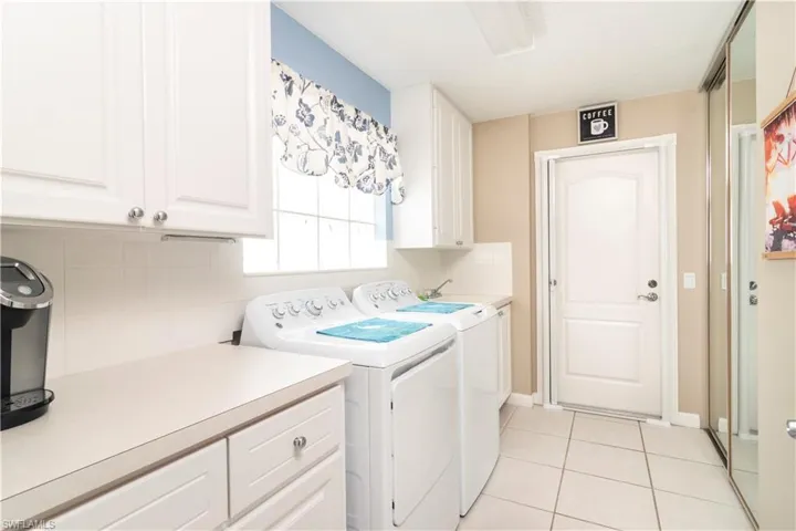 Laundry room with cabinet space, independent washer and dryer, and light tile patterned floors