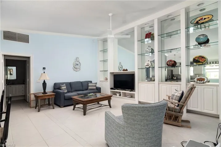 Living room with light tile patterned floors, crown molding, and built in features
