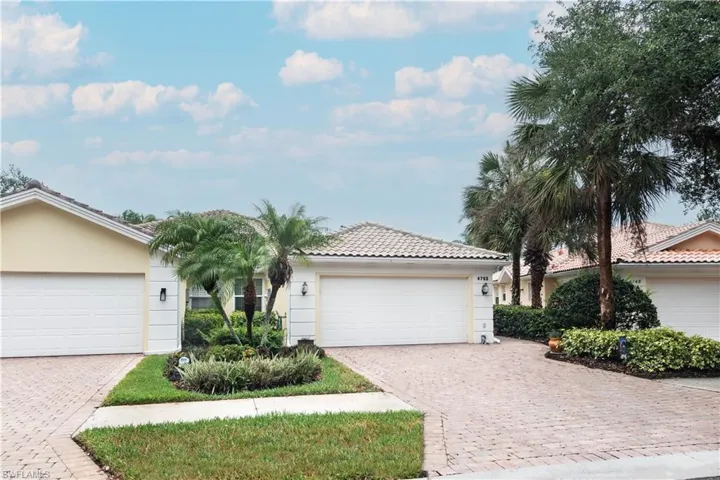 Single story home with a tiled roof, stucco siding, decorative driveway, and an attached garage