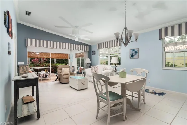Dining space with ornamental molding, light tile patterned flooring, ceiling fan, a chandelier, and baseboards