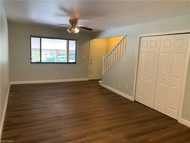 Unfurnished living room featuring ceiling fan and dark wood-type flooring