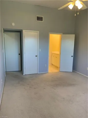 Bedroom with connected bathroom, ceiling fan, a closet, and light colored carpet