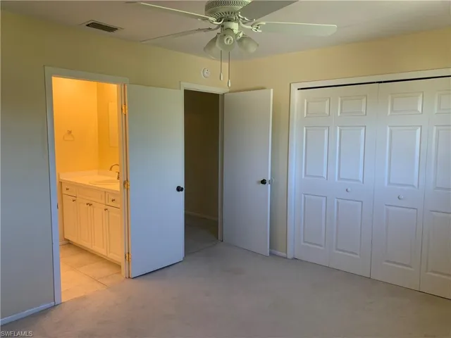 Master bedroom with light carpet, sink, ceiling fan, connected bathroom, and a closet