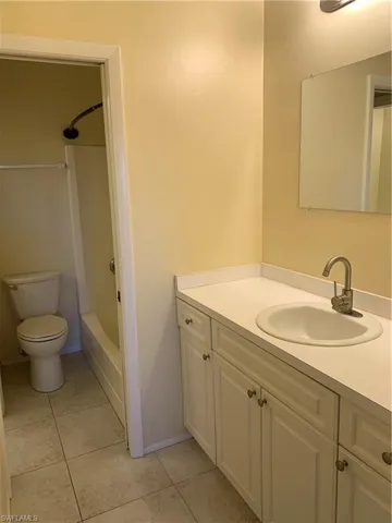 Connected bathroom with toilet, vanity, tile patterned floors, and  shower combination