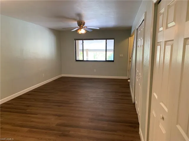 Empty room with ceiling fan and dark wood-type flooring