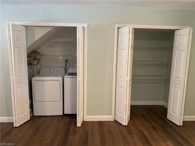 Laundry room with washer and clothes dryer and dark hardwood / wood-style floors