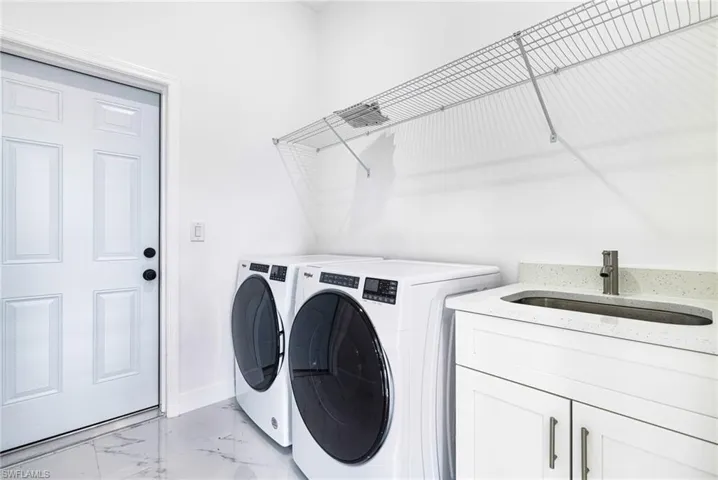 Laundry room with washer and dryer, cabinets, and sink