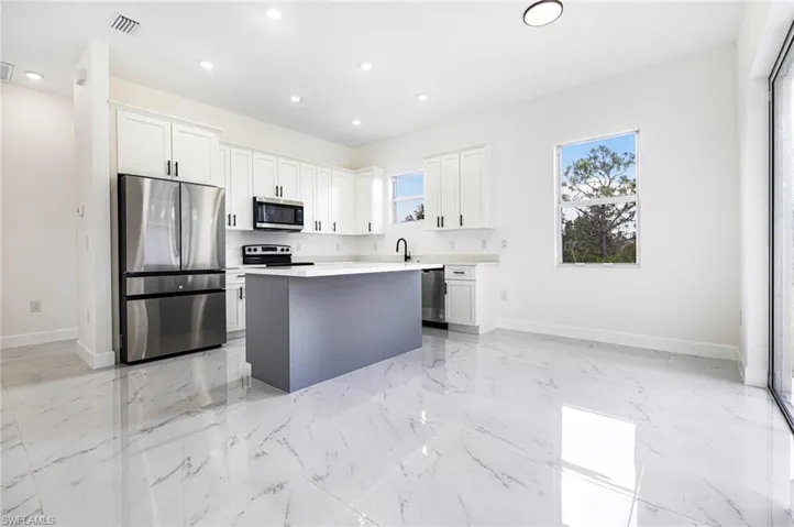 Kitchen featuring white cabinetry, stainless steel appliances, a center island, and sink