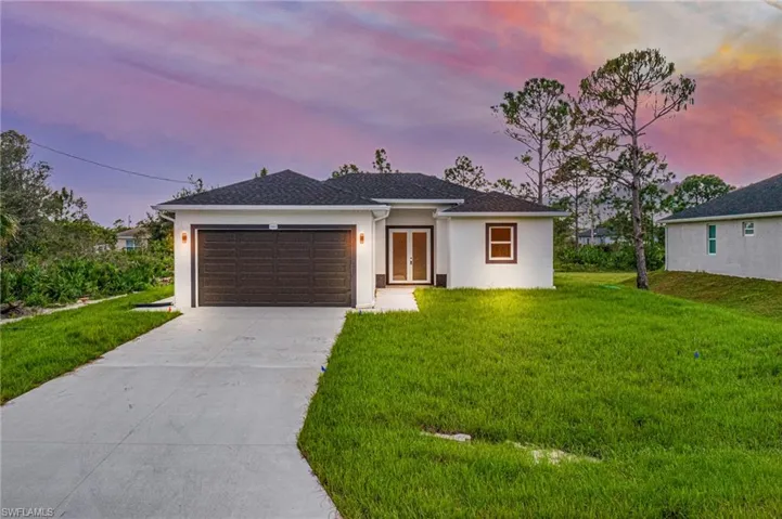 View of front of property with a garage and a lawn