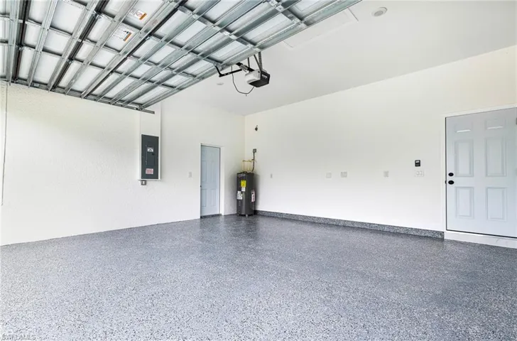 Garage featuring a garage door opener, electric water heater, and electric panel