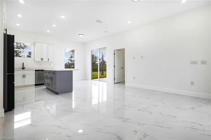 Kitchen featuring white cabinetry, a center island, dishwasher, and black fridge
