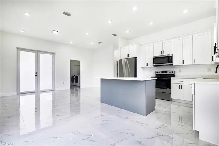 Kitchen featuring sink, a kitchen island, appliances with stainless steel finishes, and white cabinetry