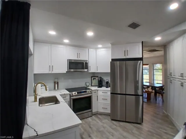 Modern kitchen with white shaker cabinetry, stainless steel appliances, and sleek countertops
