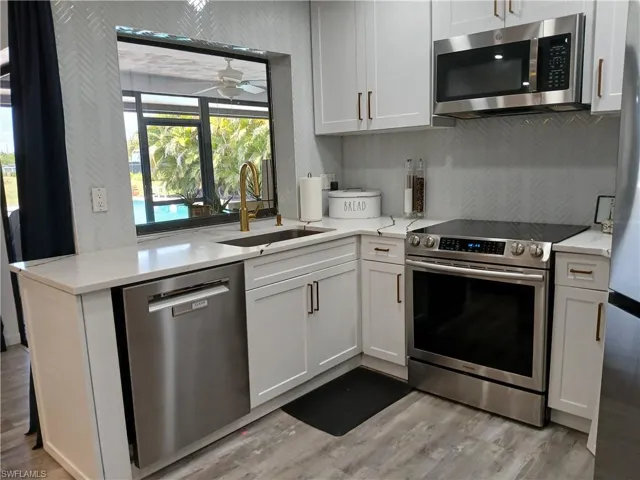 Contemporary kitchen featuring white cabinetry, stainless steel appliances, and a herringbone tile backsplash