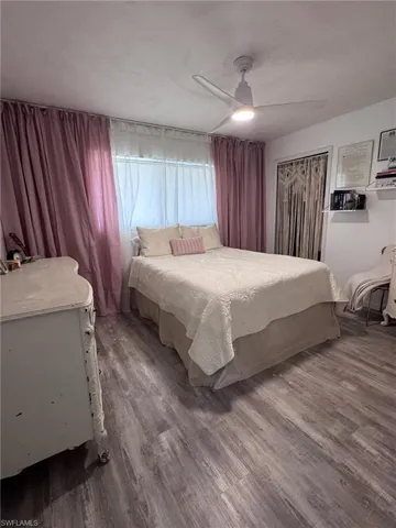 Bedroom featuring wood-finish flooring, a ceiling fan with integrated lighting, and a closet with a decorative macrame covering