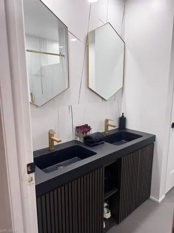 Dual vanity featuring matte black sinks and gold-finish faucets