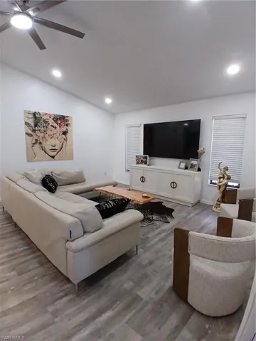 Spacious living area featuring wood-finish flooring, recessed lighting, and a sloped ceiling with a ceiling fan