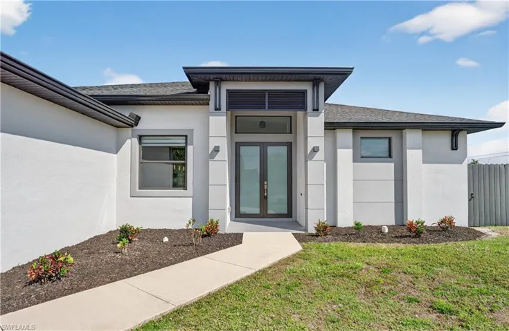 Property entrance featuring stucco siding, french doors, a lawn, and a shingled roof