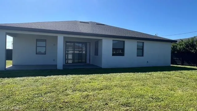 Back of house with a yard, a patio, and stucco siding